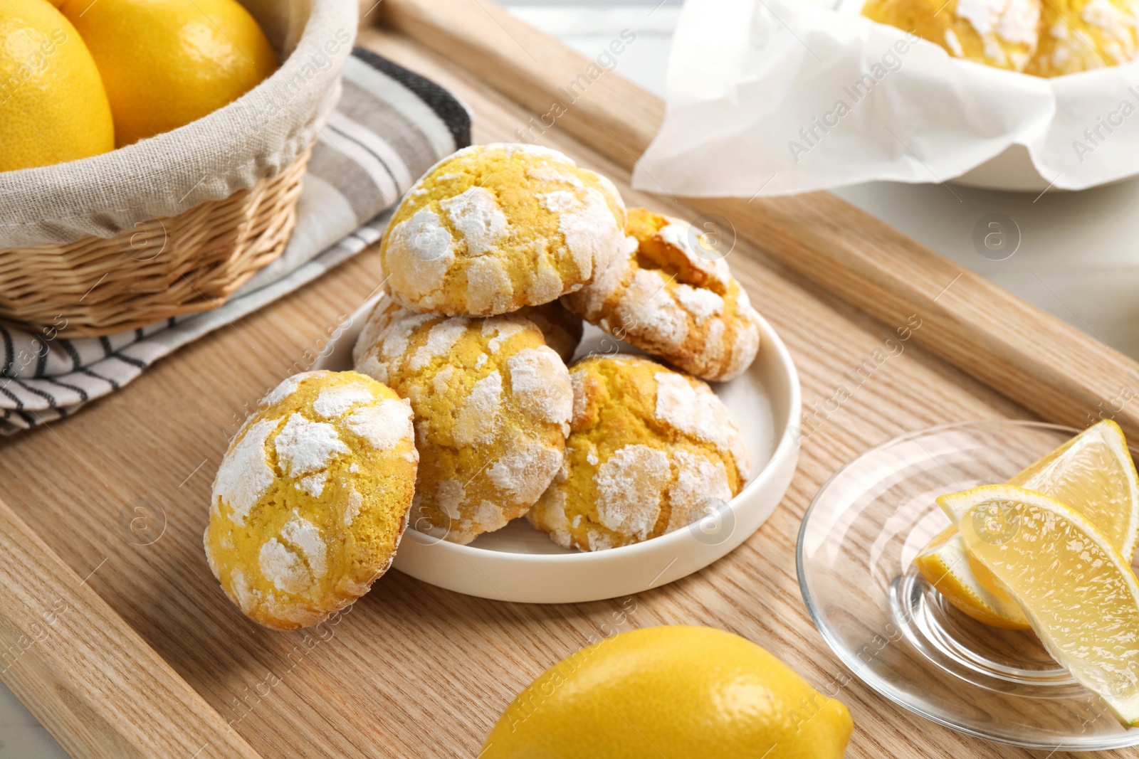 Photo of Tasty homemade lemon cookies and fresh fruits on wooden tray