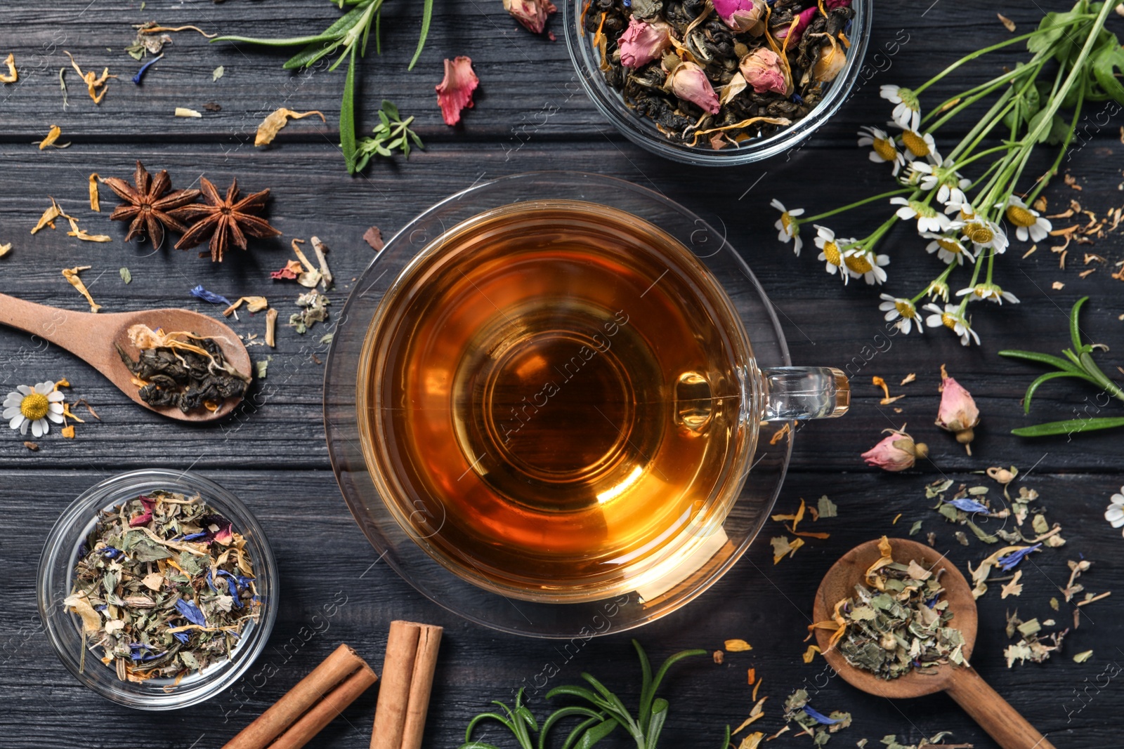 Photo of Flat lay composition with freshly brewed tea and dry leaves on black wooden table