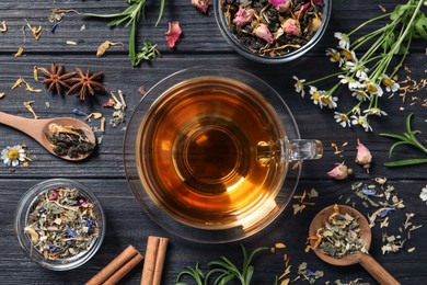 Flat lay composition with freshly brewed tea and dry leaves on black wooden table