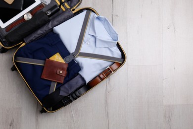 Photo of Packed suitcase with business trip stuff on wooden surface, top view. Space for text
