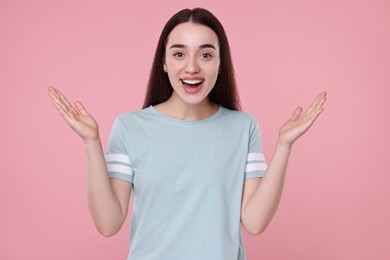 Photo of Portrait of happy surprised woman on pink background