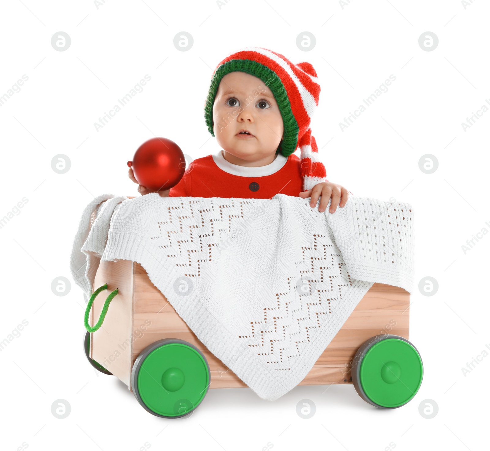 Photo of Cute little baby wearing elf hat in wooden cart on white background. First Christmas