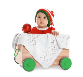 Cute little baby wearing elf hat in wooden cart on white background. First Christmas