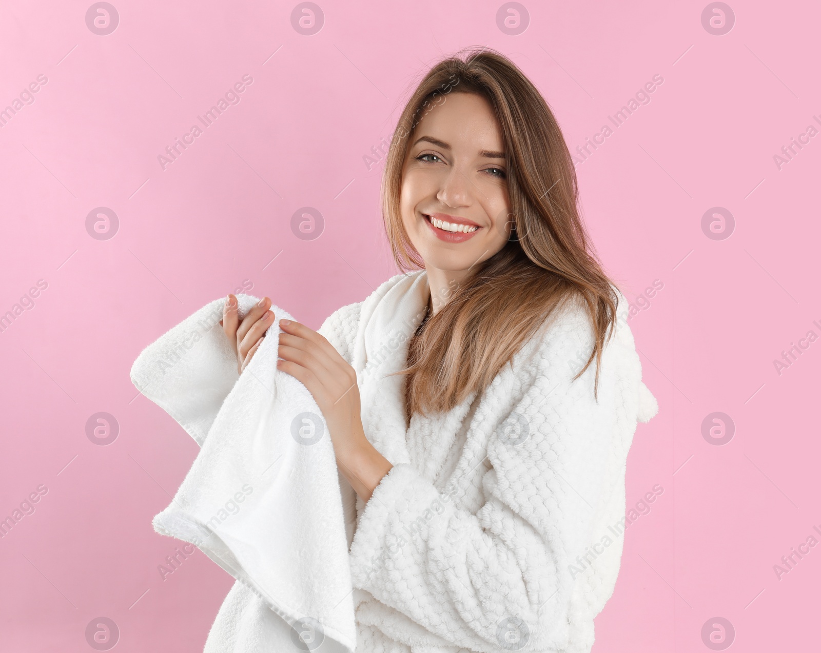 Photo of Young woman wiping hands with towel on light pink background