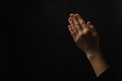 Religion. Christian woman praying on black background, closeup. Space for text