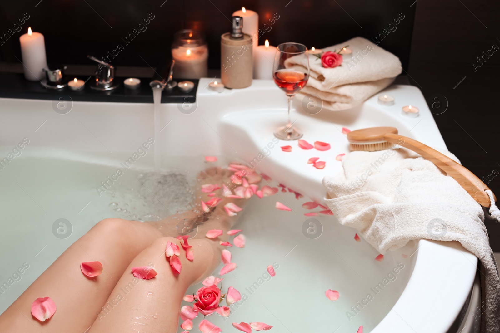 Photo of Woman taking bath with rose petals, closeup. Romantic atmosphere