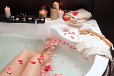 Photo of Woman taking bath with rose petals, closeup. Romantic atmosphere