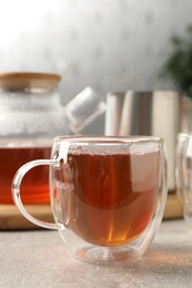 Aromatic tea in glass cup on light grey table