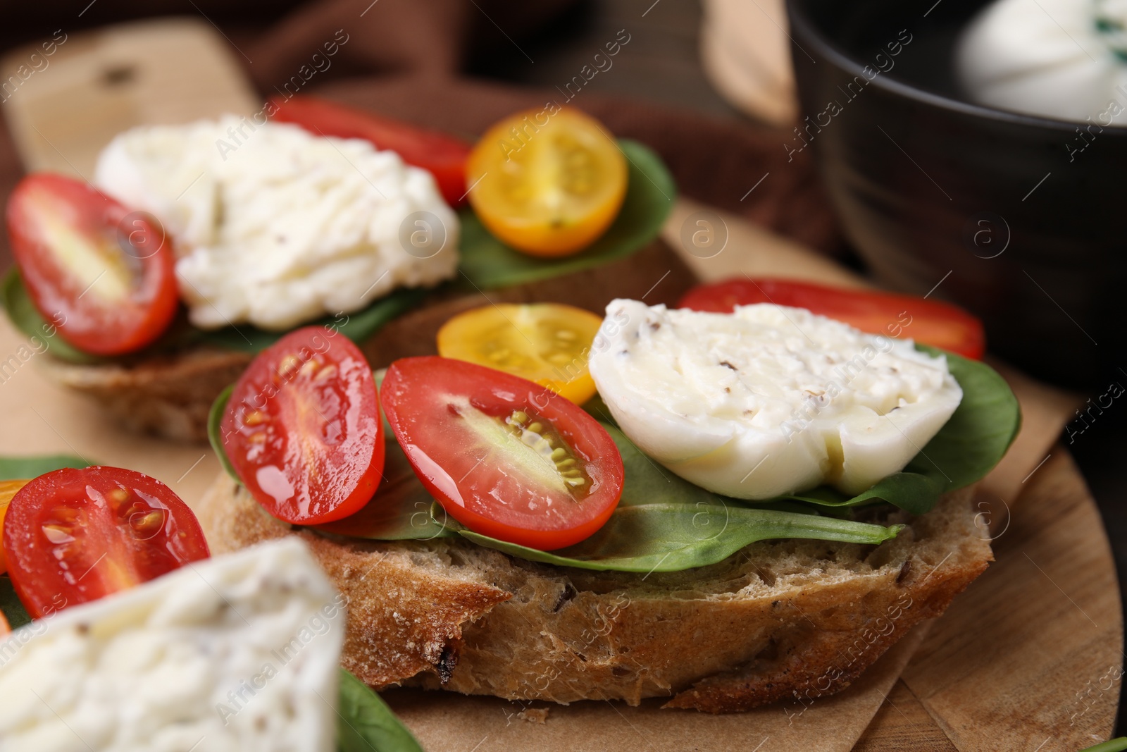 Photo of Delicious sandwiches with burrata cheese and tomatoes on board, closeup