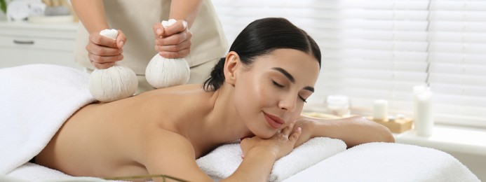 Young woman receiving herbal bag massage in spa salon. Banner design