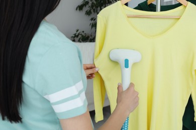 Woman steaming yellow shirt at home, closeup