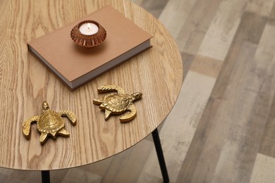 Book, candle and decor on wooden round table indoors, closeup. Space for text