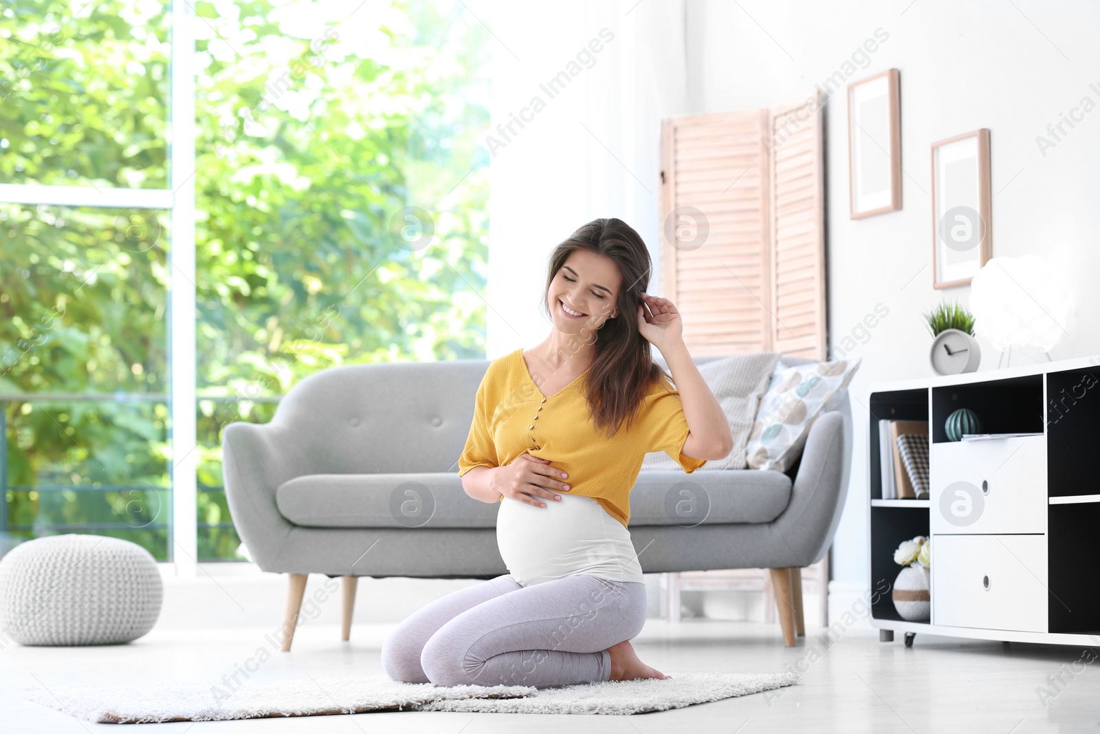 Photo of Happy pregnant woman sitting on floor at home