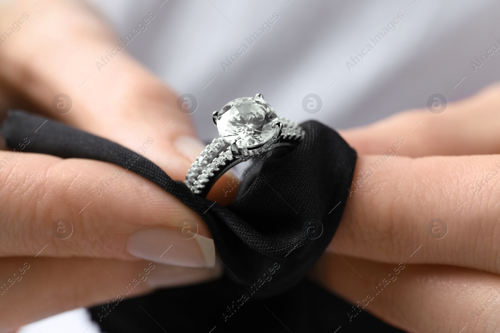 Photo of Jeweler cleaning diamond ring with microfiber cloth, closeup