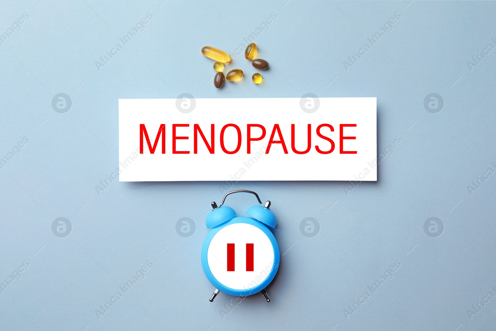 Image of Menopause word, alarm clock with pause symbol and pills on light blue background, top view