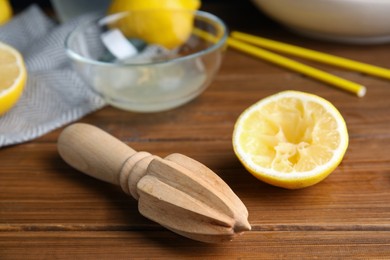 Photo of Citrus reamer and fresh lemons on wooden table