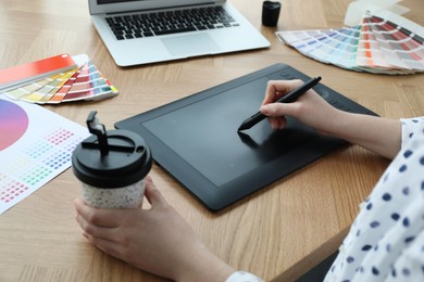 Professional designer with graphic tablet at wooden table, closeup