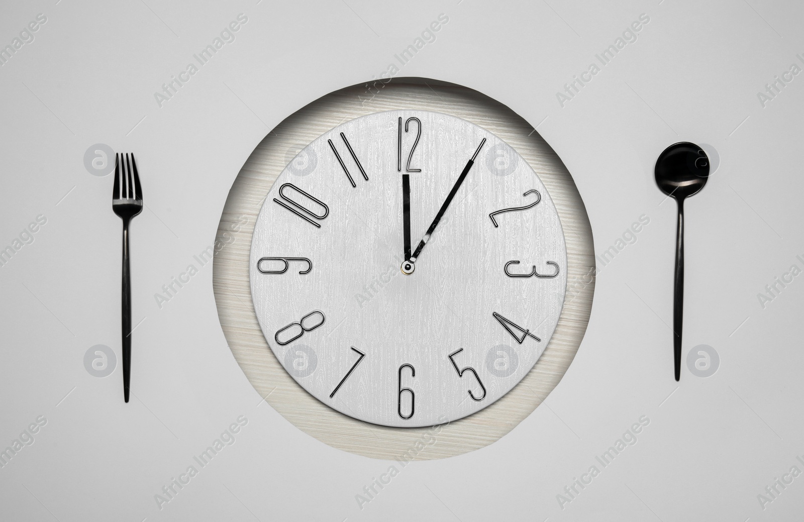 Photo of Creative business lunch layout. Composition with clock and cutlery on white wooden background