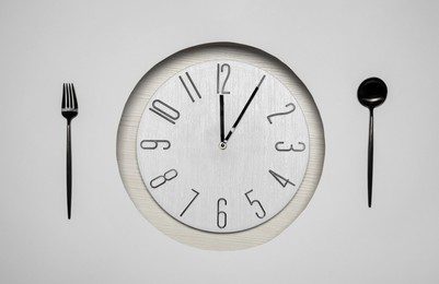 Creative business lunch layout. Composition with clock and cutlery on white wooden background