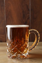 Mug with fresh beer on wooden table