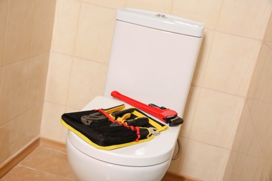 Photo of Different plumber's tools on toilet seat lid indoors