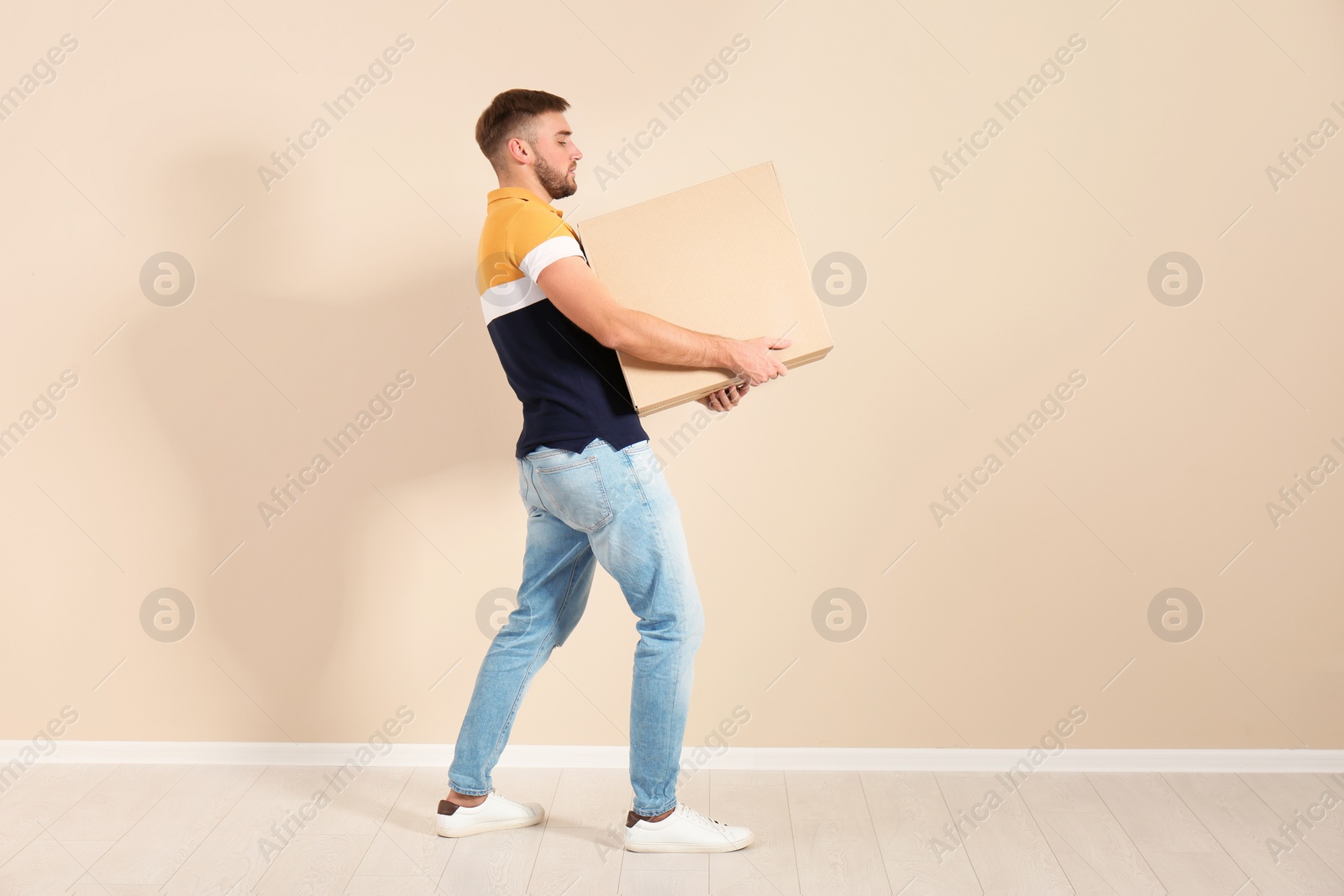 Photo of Full length portrait of young man carrying carton box near color wall. Posture concept