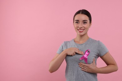 Photo of Beautiful young woman with pink ribbon on color background, space for text. Breast cancer awareness