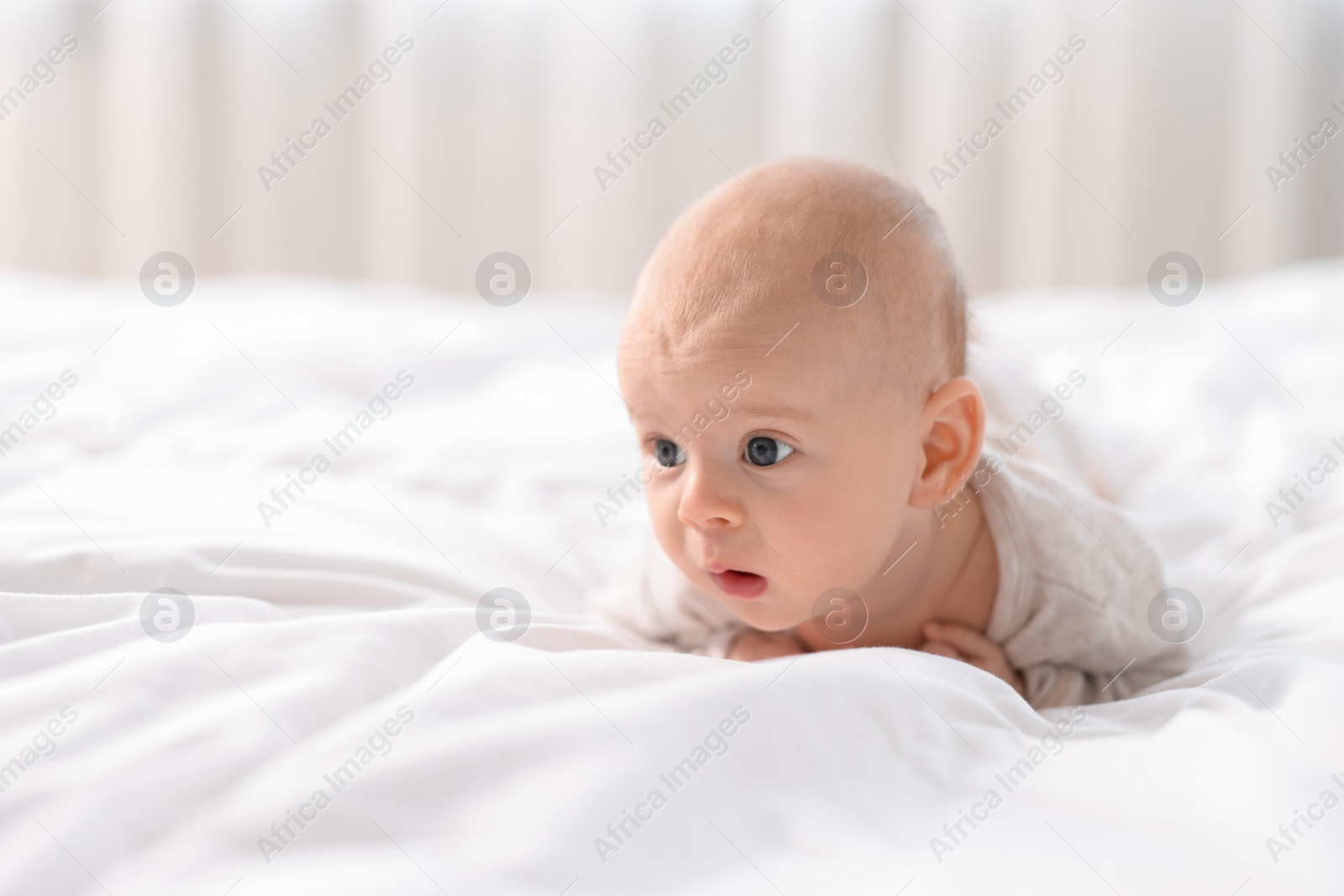 Photo of Cute little baby lying on white sheets, space for text