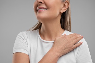 Mature woman with healthy skin on grey background, closeup