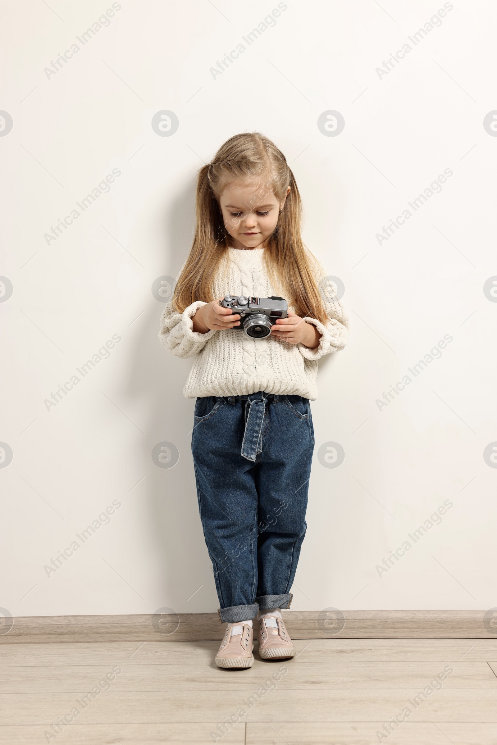 Photo of Fashion concept. Stylish girl with vintage camera near white wall