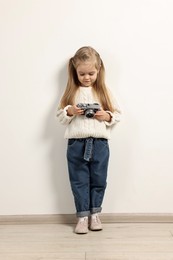 Fashion concept. Stylish girl with vintage camera near white wall