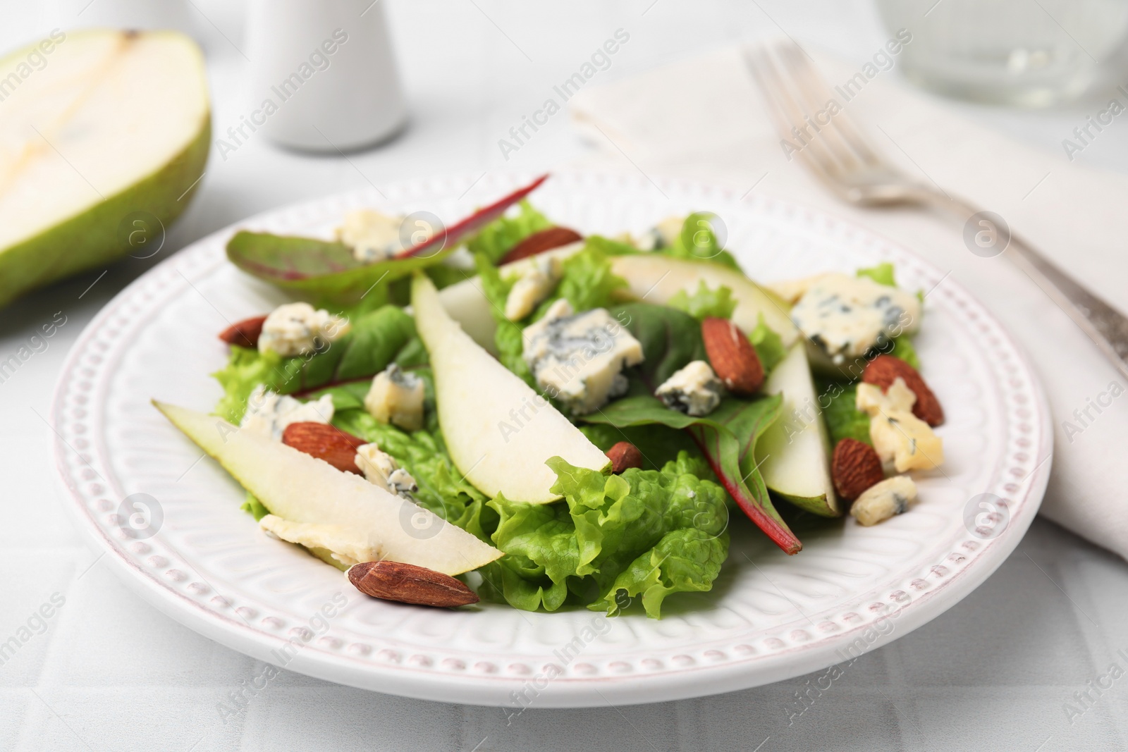 Photo of Delicious pear salad on white tiled table, closeup