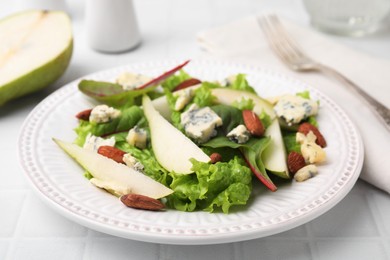 Photo of Delicious pear salad on white tiled table, closeup