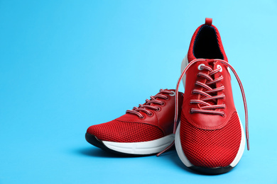 Stylish red sneakers on light blue background. Space for text