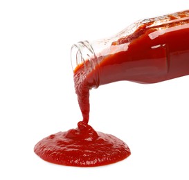 Pouring tasty red ketchup from glass bottle isolated on white
