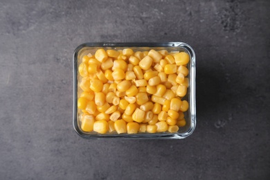 Bowl with corn kernels on grey background, top view