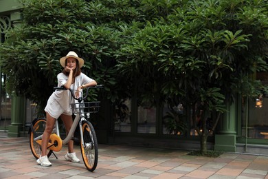 Photo of Beautiful young woman with bicycle outdoors. Space for text