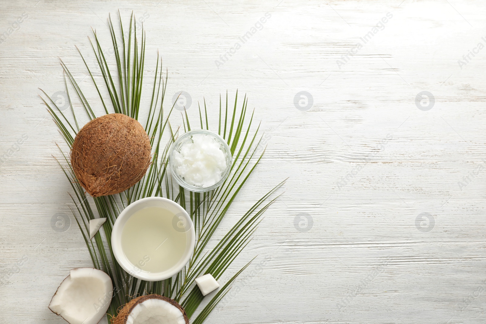 Photo of Flat lay composition with coconut oil on white wooden table, space for text