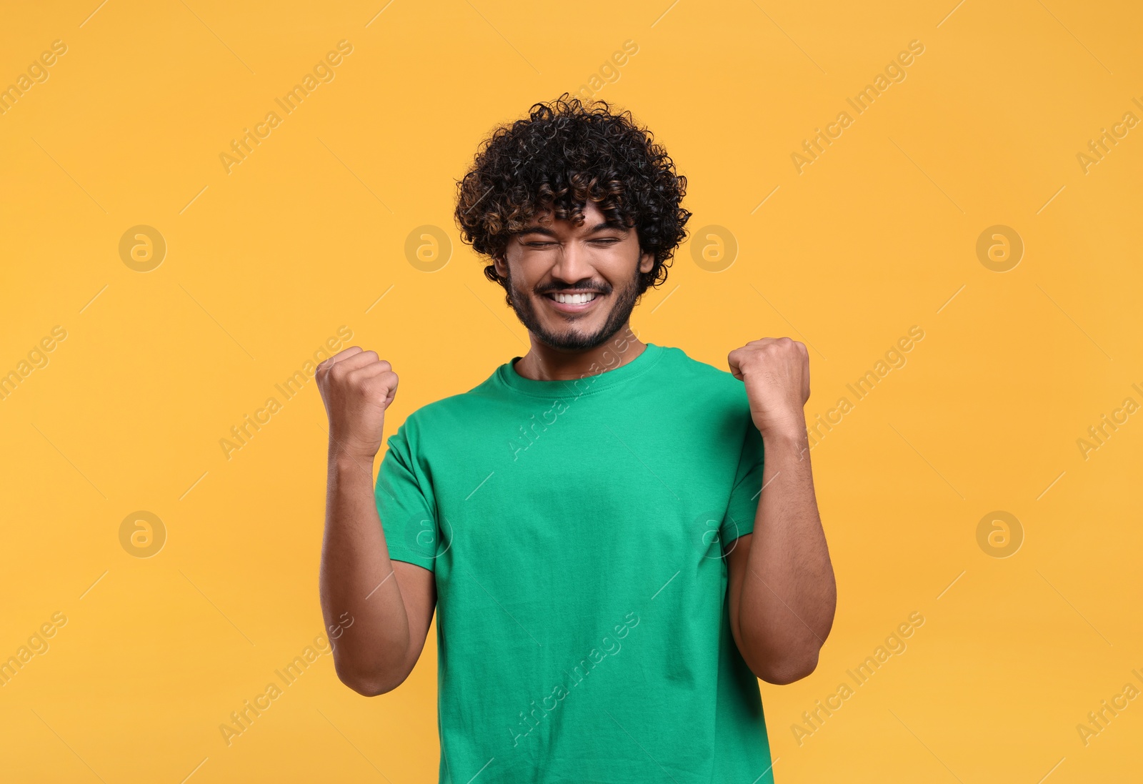 Photo of Handsome young happy man on yellow background