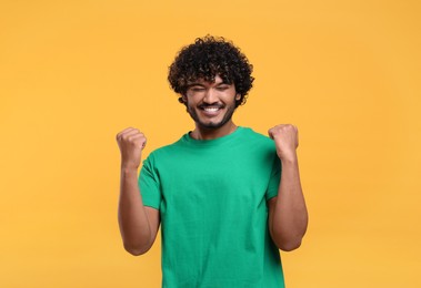 Photo of Handsome young happy man on yellow background