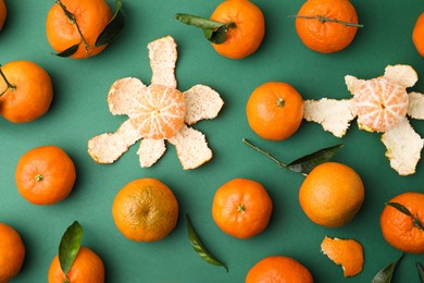 Photo of Many fresh ripe tangerines and leaves on green table, flat lay