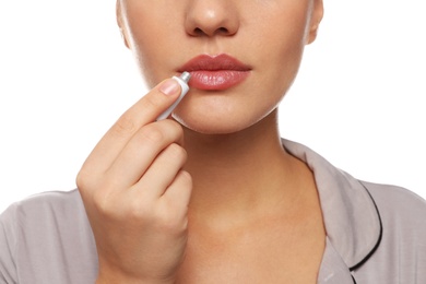 Photo of Woman with herpes applying cream on lips against white background, closeup