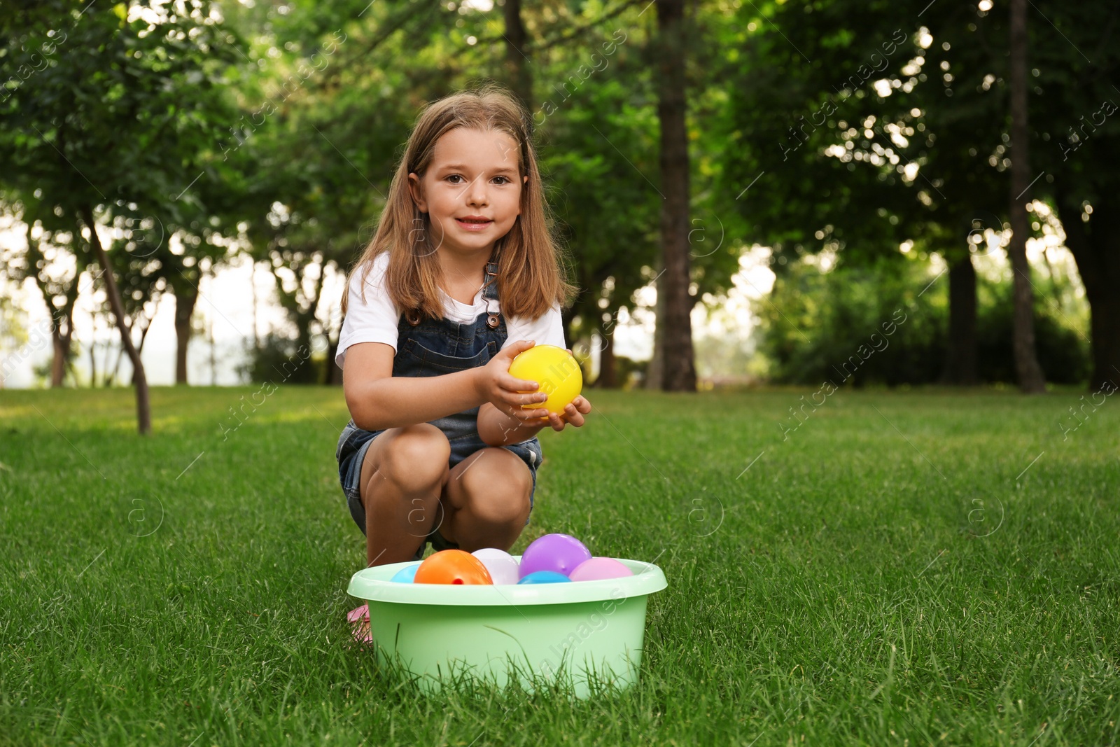 Photo of Little girl with basin of water bombs in park