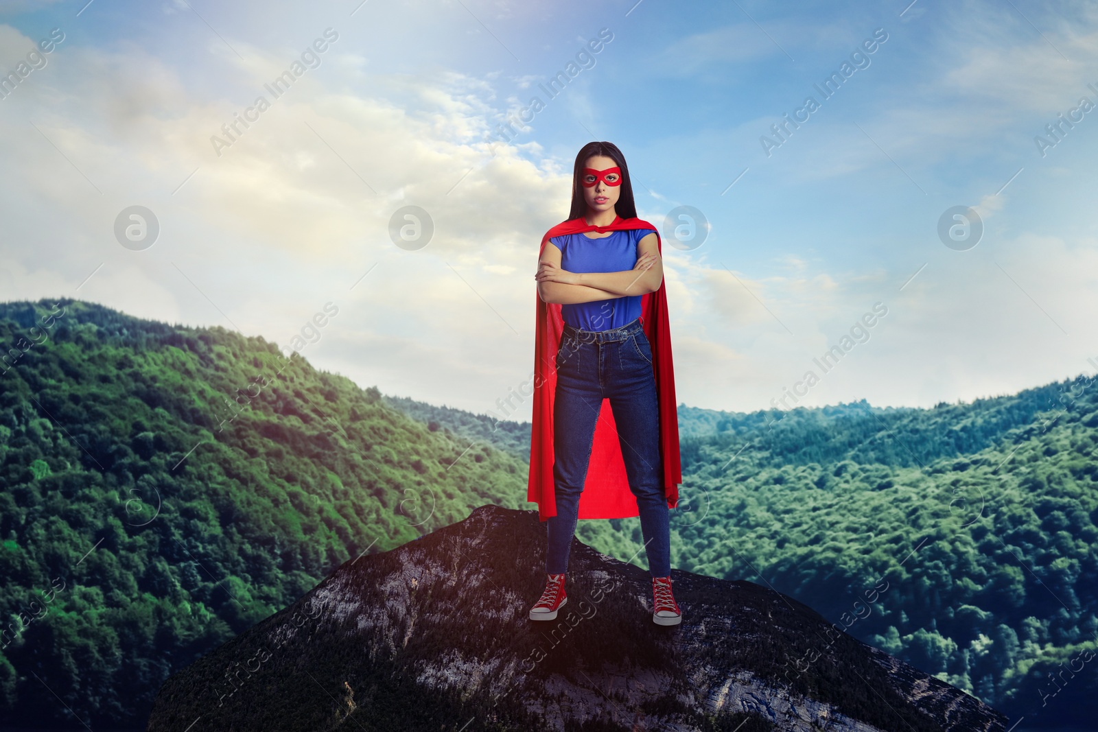 Image of Superhero, motivation and power. Woman in cape and mask on high top in mountains