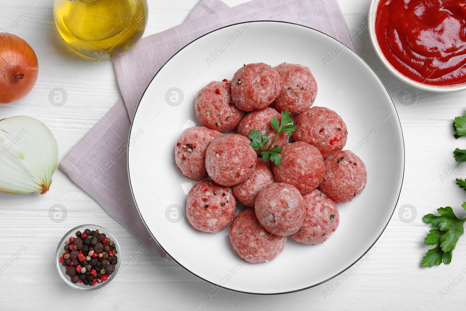 Photo of Many fresh raw meatballs and ingredients on white wooden table, flat lay