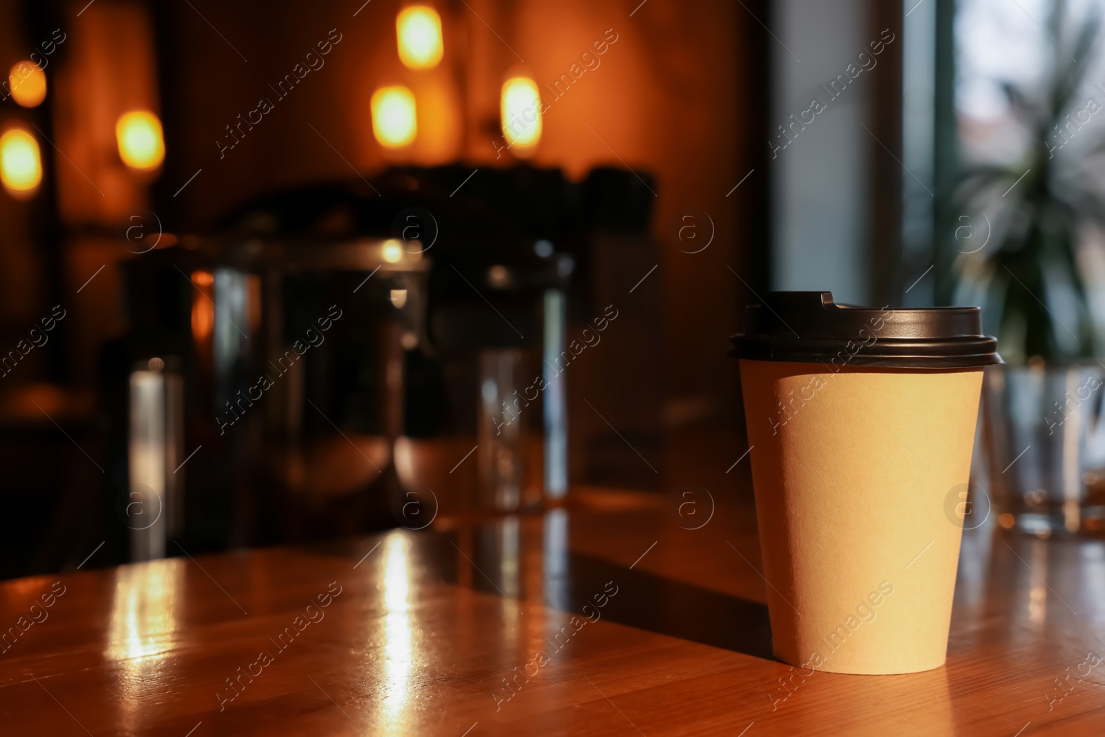 Photo of Paper coffee cup on wooden table in cafe. Space for text