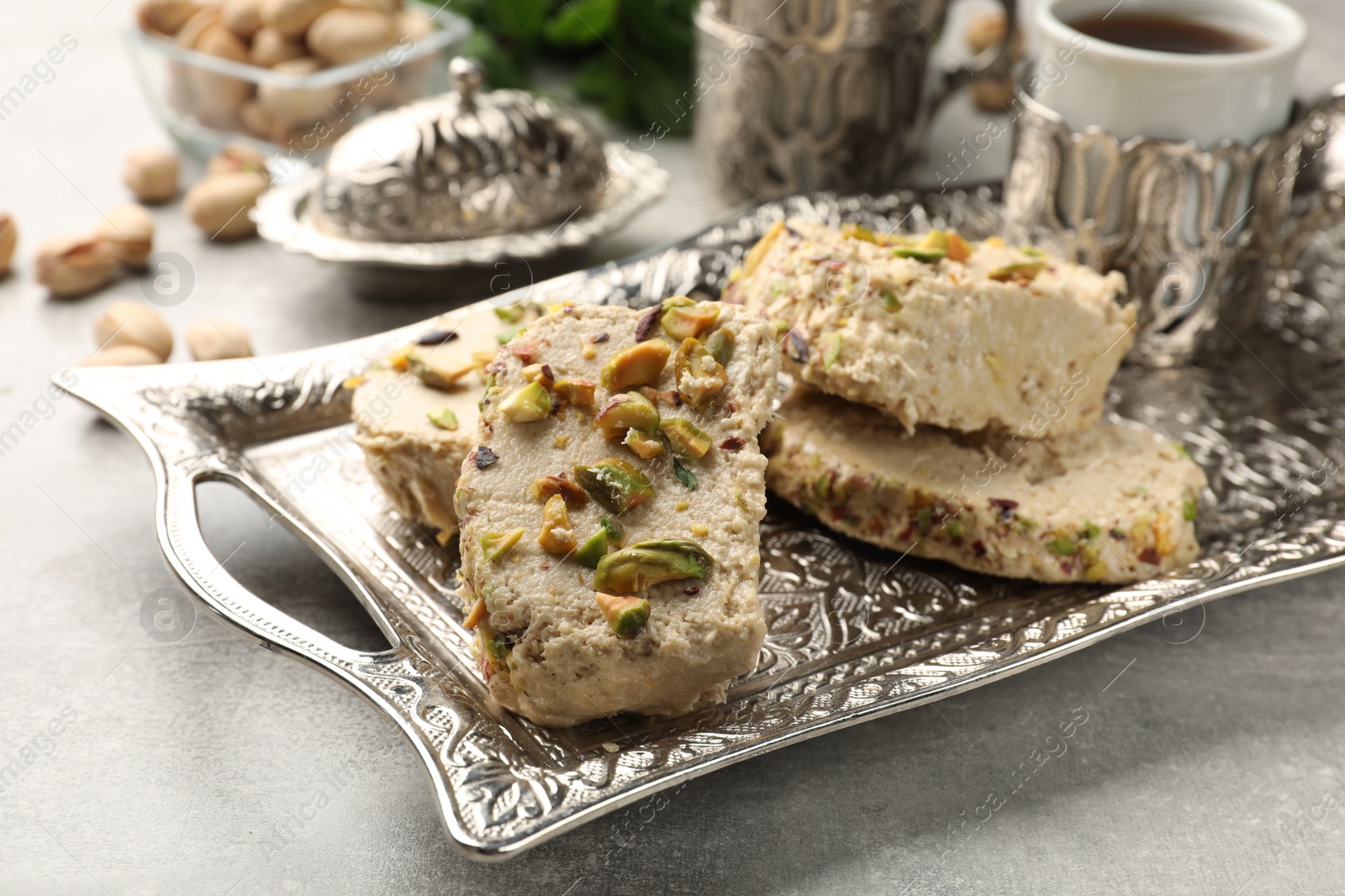 Photo of Tasty pistachio halva served on light grey table, closeup