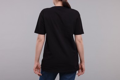 Woman in stylish black t-shirt light grey on background, back view