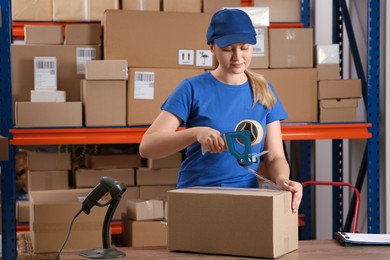 Photo of Post office worker packing parcel near rack indoors