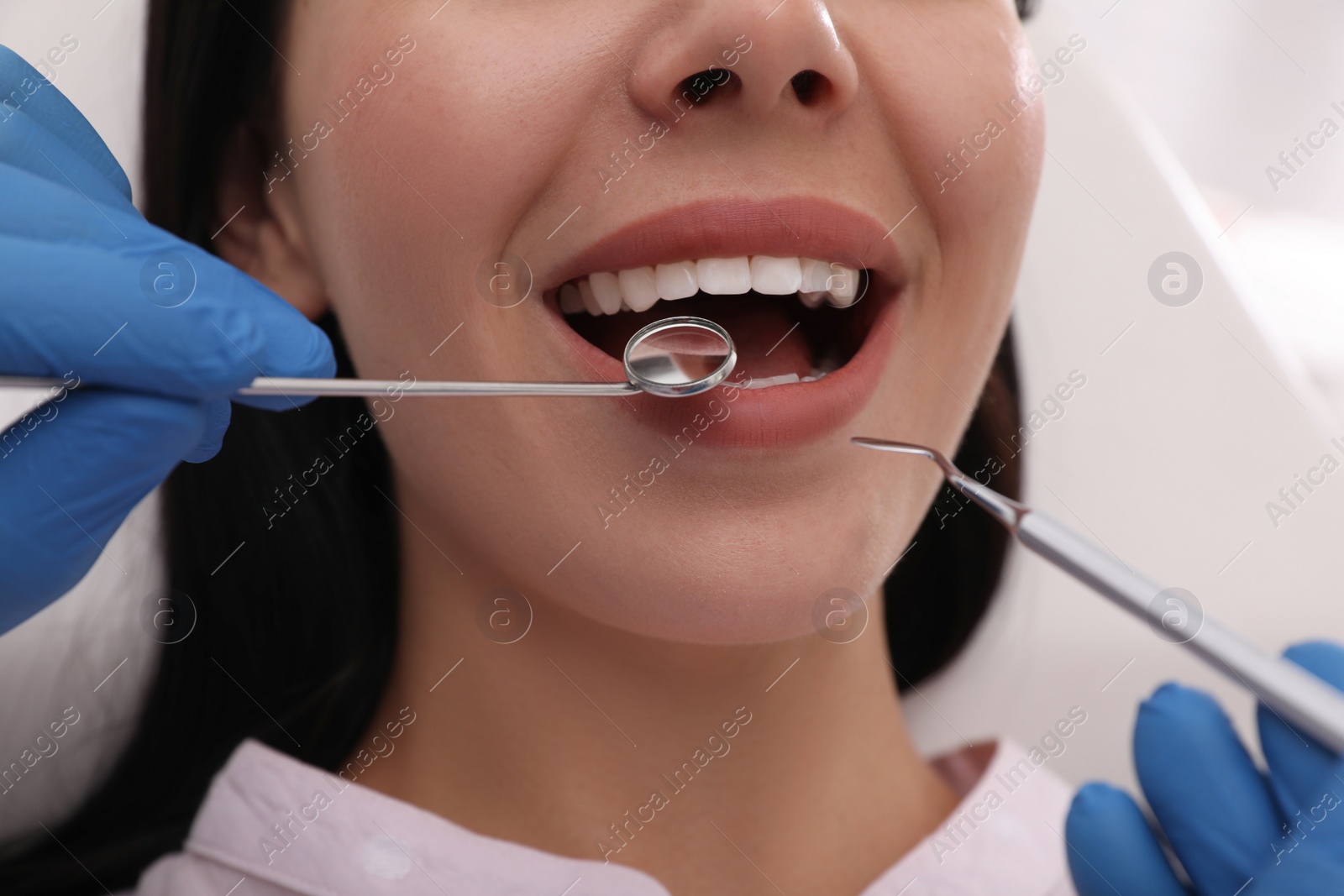 Photo of Dentist examining young woman's teeth, closeup view